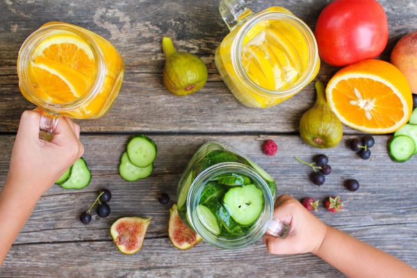 Children's hands take drinks with fruit and vegetables © Adobe Stock